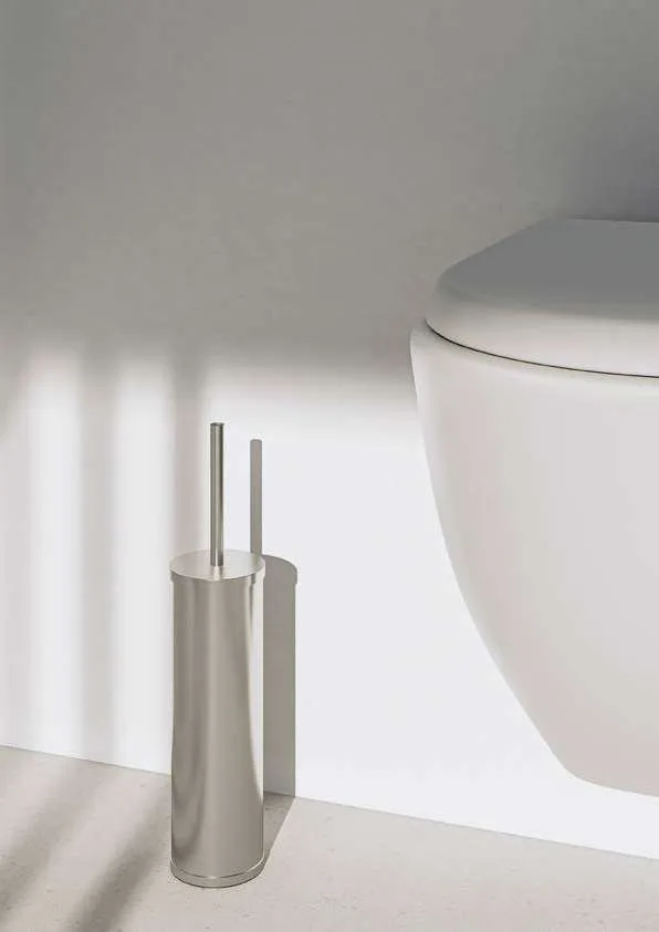 Brosse WC en inox posée au sol à côté d’une cuvette suspendue
