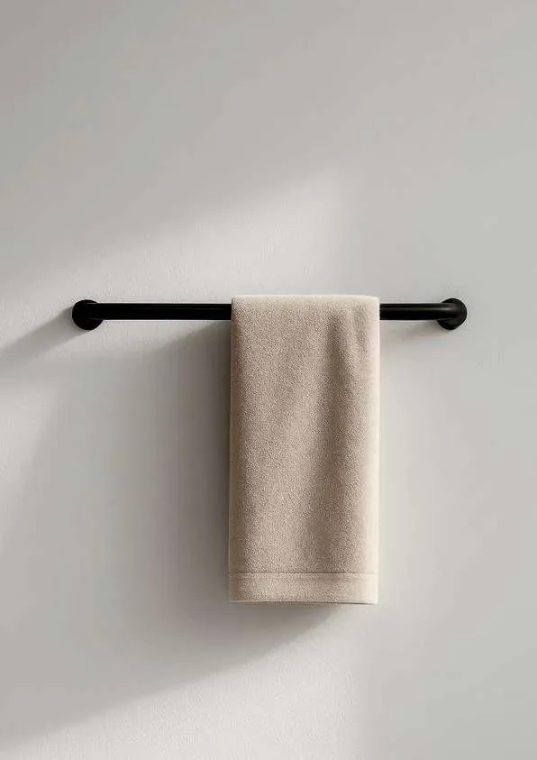 Matt black towel rail with a beige towel in a light bathroom
