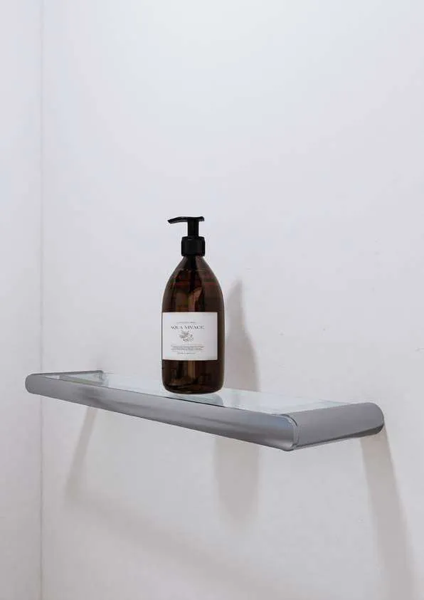 Wall-mounted glass shelf with a soap bottle on it