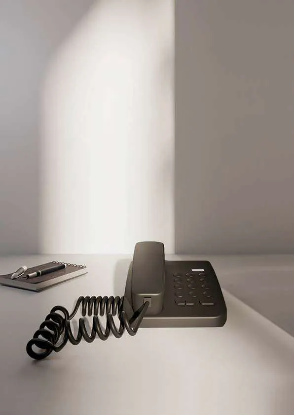 Téléphone de chambre gris foncé à cordon spiralé sur un bureau
